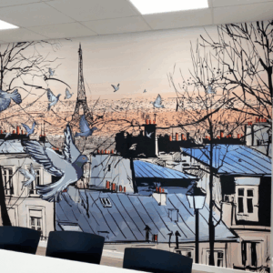 Maleri på kontor væg, lavet i blå, hvide og creme nuancner. Det skitsere tagtoppe fra Paris, alle i blå toner, og med fugle som flyver i forgrunden.