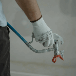 Maler med handske holder sprøjtepistol under professionel sprøjtemaling